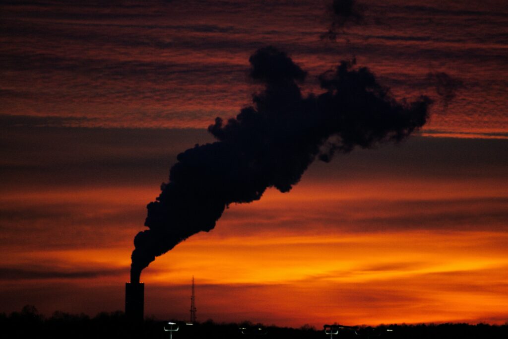 steam billows from a factory at sunset